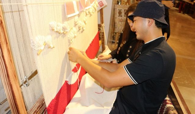 Isparta’da yerli ve yabancı ziyaretçiler ilmek ilmek Türk Bayrağı halısı dokuyor